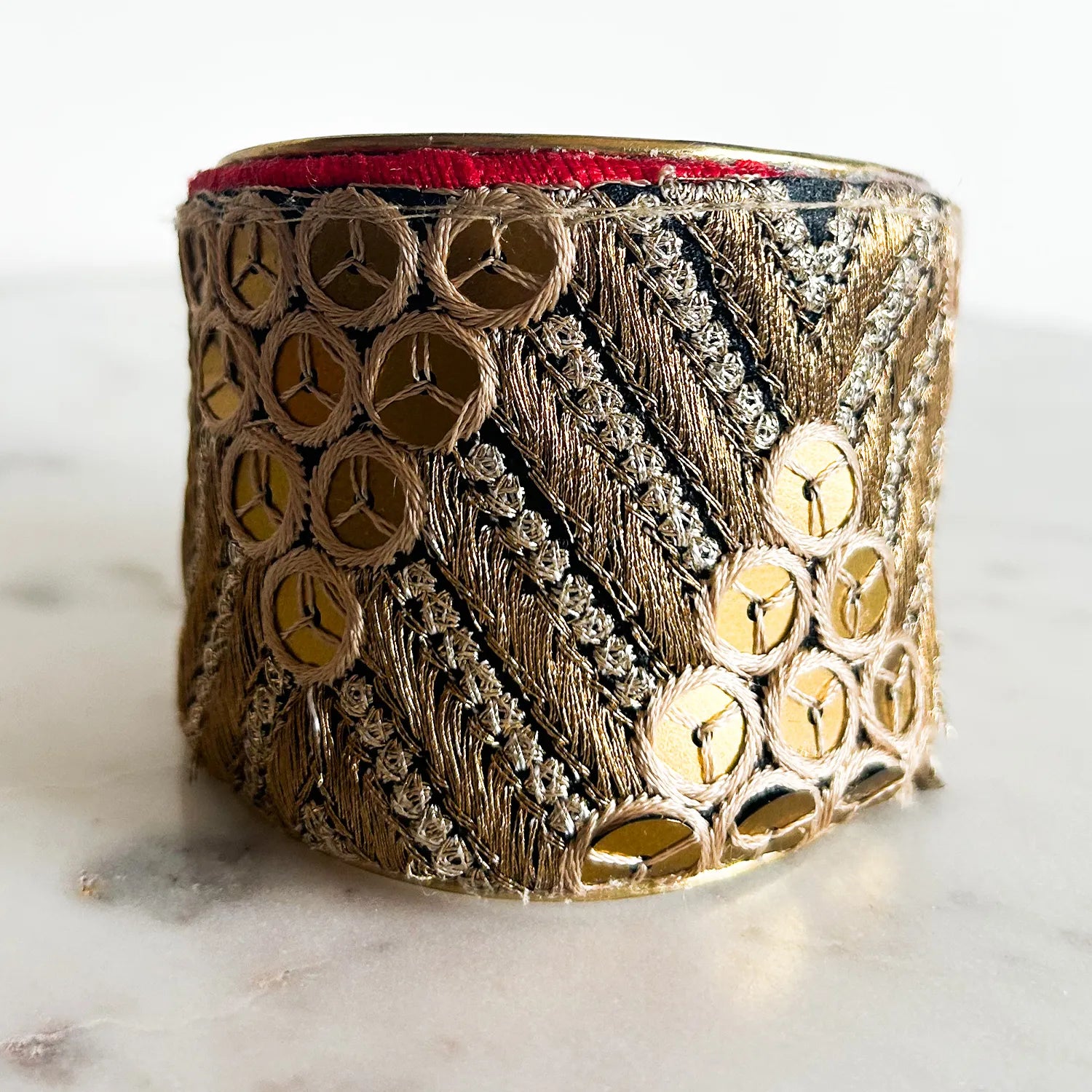 Close-up of Athena Brass Cuff Bracelet with gold chevron embroidery and red edge, handcrafted in Shreveport, LA by Redd Dott Jewelry.