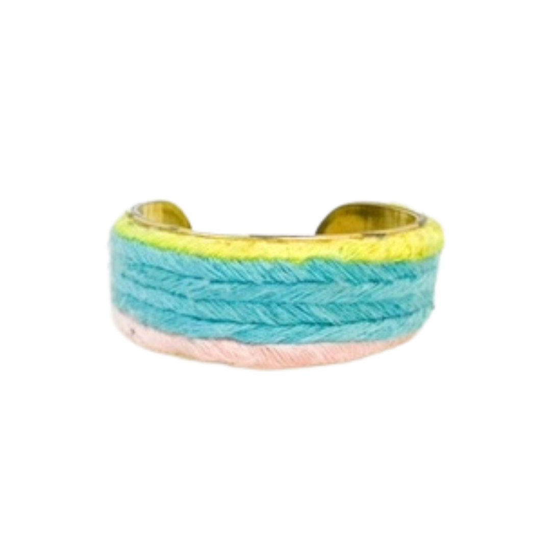 A studio image of a one of a kind jewelry brass cuff bracelet for women—a 1-inch wide open-back design wrapped in hand-dyed pastel yarn in mint, peach, and lemon, displayed on a white background.