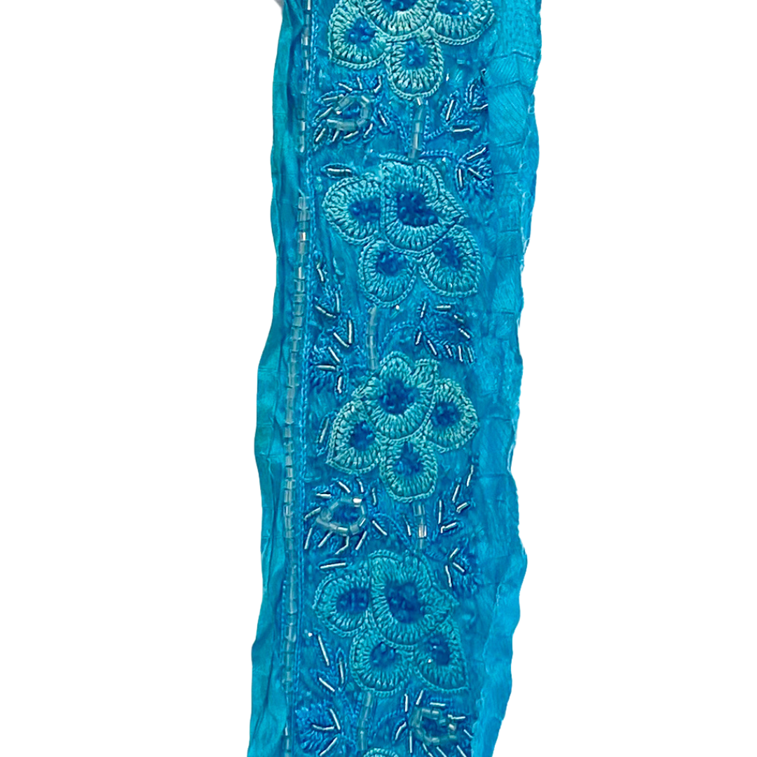 A beaded flower bracelet by Redd Dott Jewelry, featuring intricate blue floral embroidery with delicate beadwork.