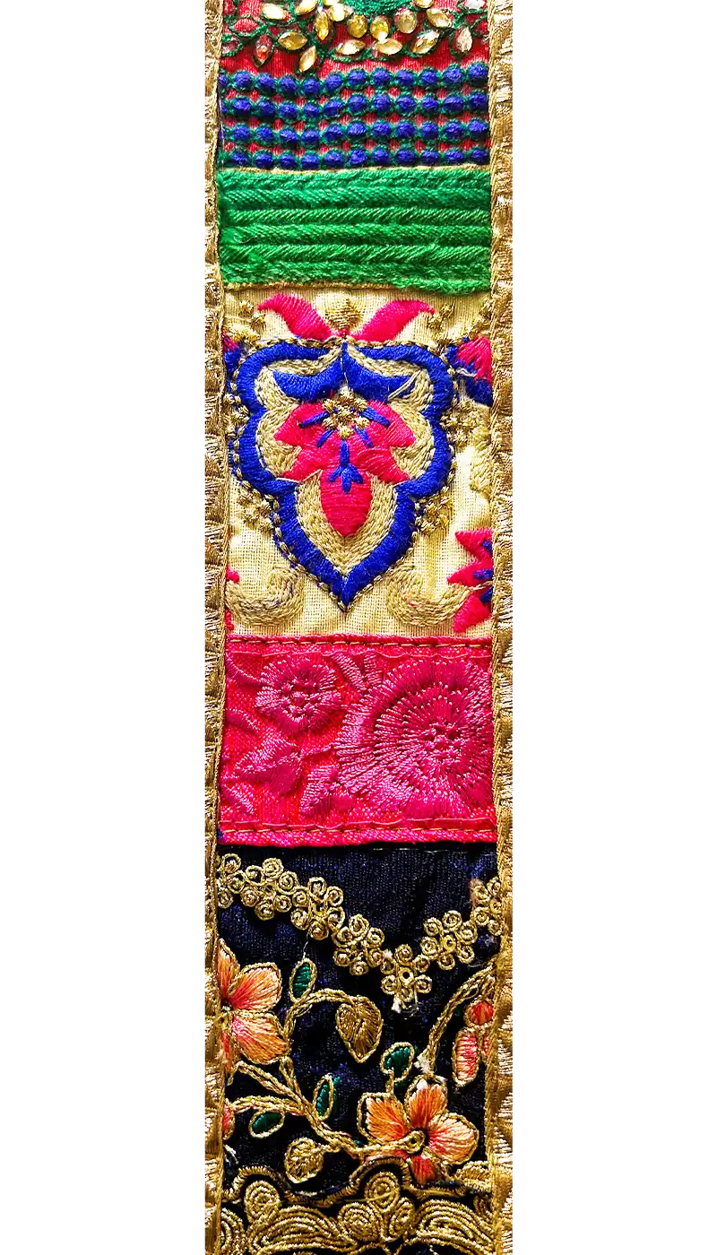 Close-up of embroidered vintage fabric used in the Ashari Brass Cuff Bracelet, featuring cream, gold, red, green, and violet stitching, handcrafted in Shreveport, LA by Redd Dott Jewelry.