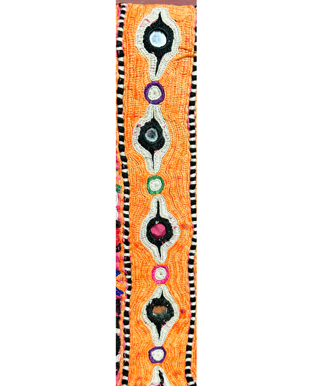 A handcrafted custom stamped cuff bracelet by Redd Dott Jewelry featuring orange vintage kaftan fabric with bold embroidered motifs and mirror accents. A vibrant and textural vintage brass bracelet.