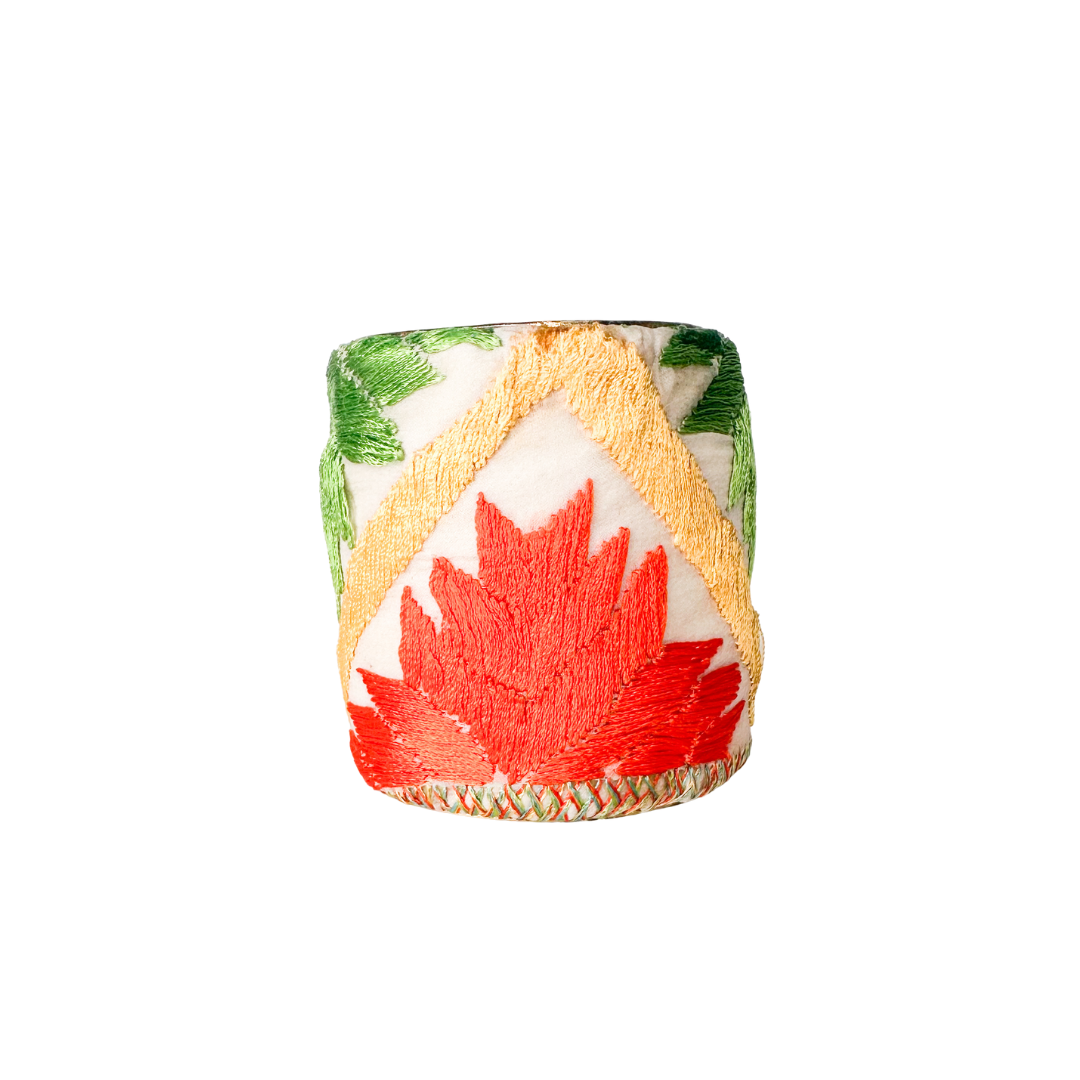 Geometric cuff bracelet with bold embroidered patterns in green, orange, and yellow, featuring a distinctive leaf motif and a modern, angular design.