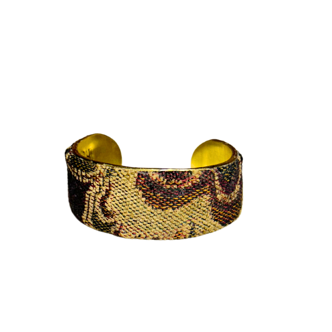 A handcrafted brass cuff bracelet by Redd Dott Jewelry wrapped in neutral floral tapestry fabric with subtle scroll detail. A refined and understated vintage brass bracelet.