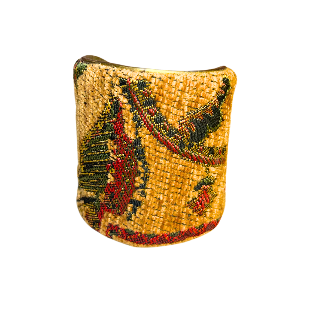A handmade brass cuff bracelet from Redd Dott Jewelry, crafted and stamped in Shreveport, LA. Features a golden woven base with flowing accents of red, green, and black, creating a vintage, rustic cuff bracelet look.