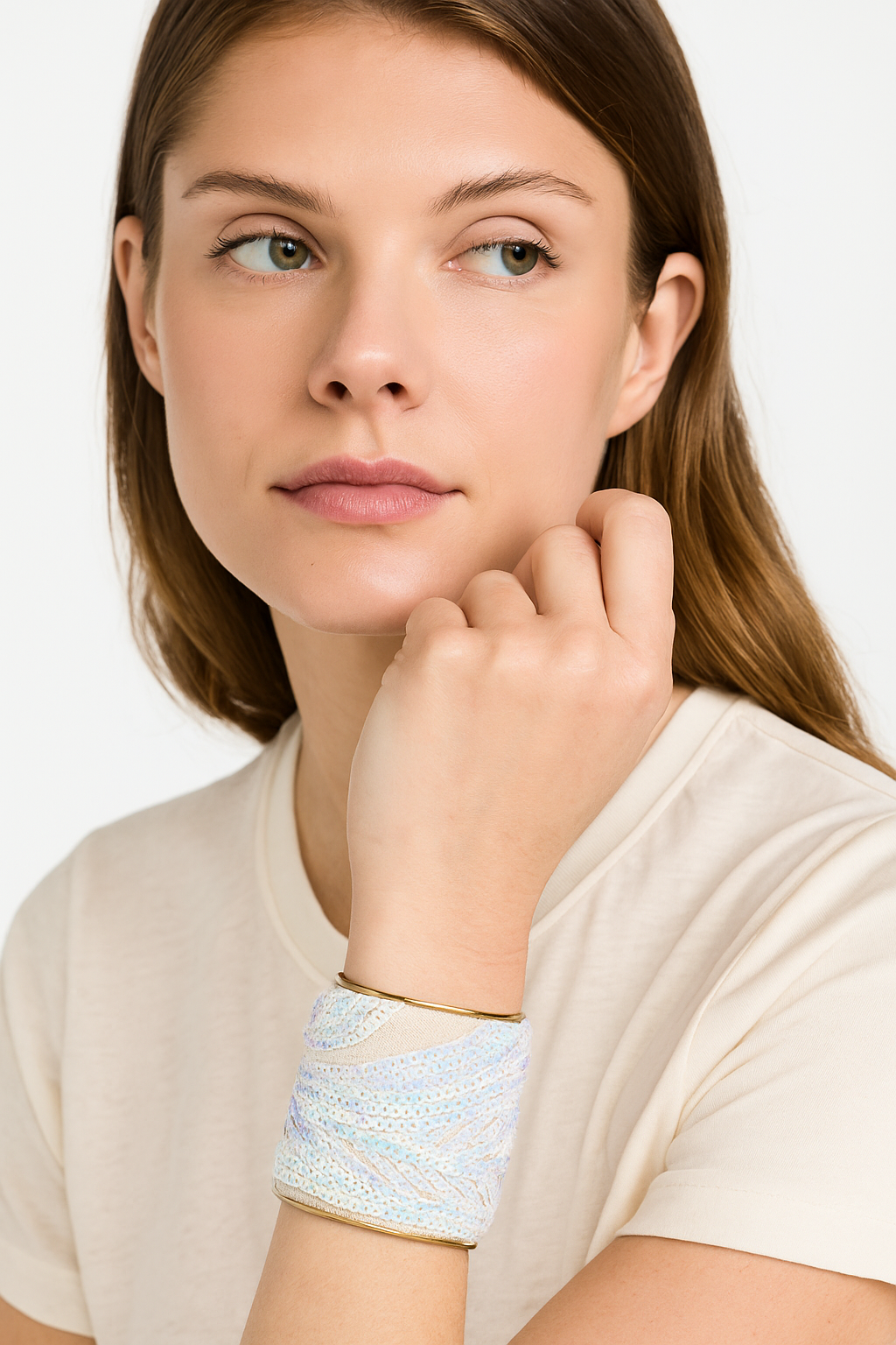A female model wearing a 3-inch wide raw brass cuff bracelet wrapped in ivory mesh, covered in pastel iridescent sequins in a wave pattern. The open-back design makes this brass cuff bracelet an elegant, one of a kind jewelry piece and a top pick in cuff bracelets for women.