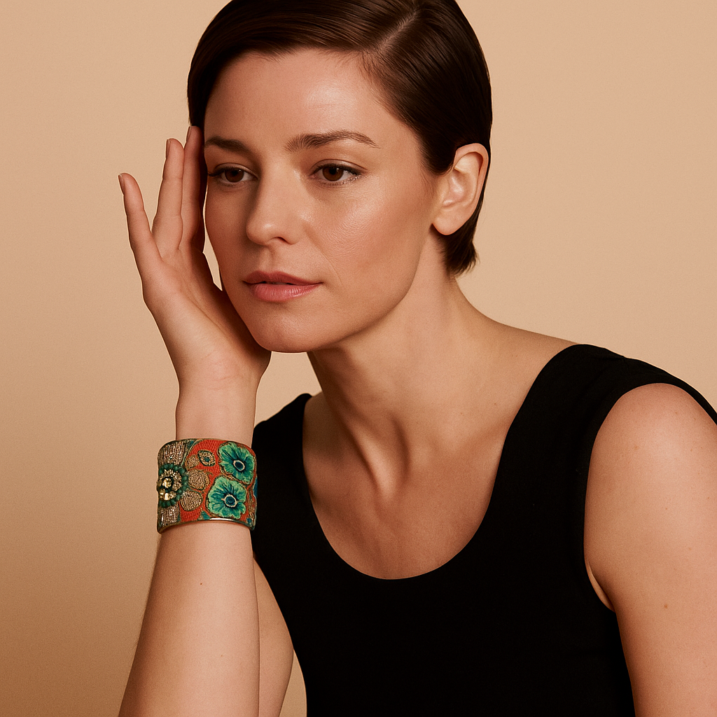 Bright floral embroidered brass cuff bracelet with gold-thread petals and a central raised flower detail, on a model.