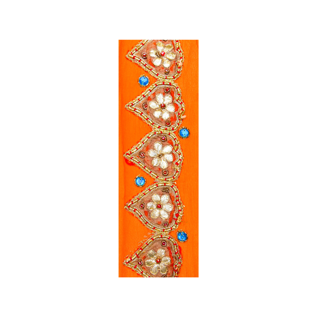 Clemence custom floral cuff bracelet – bright orange fabric with heart-shaped embroidered flowers, orange beadwork, and blue gem accents on a brass base.