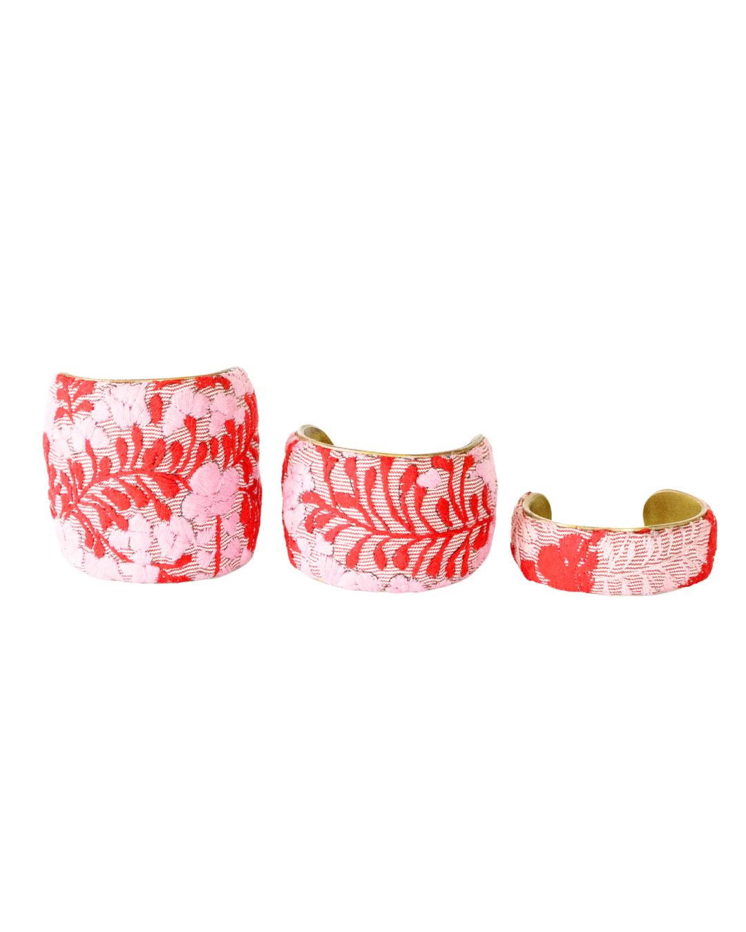 Three Corazón Rojo brass cuff bracelets in 1-, 2-, and 3-inch sizes featuring red and pink floral embroidery on soft striped fabric.