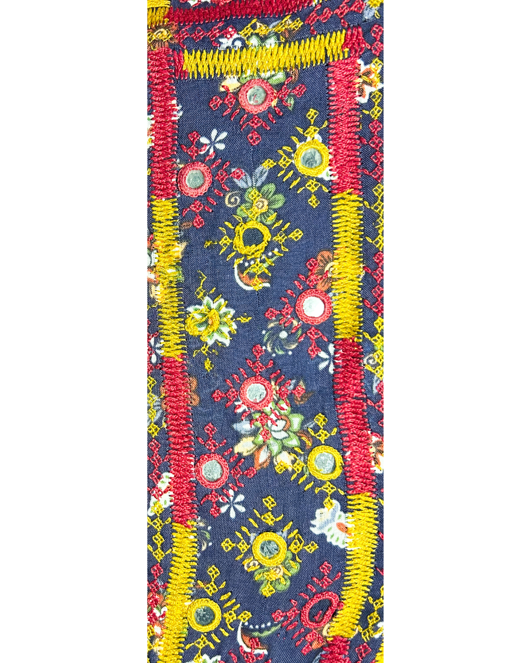 A handcrafted custom stamped cuff bracelet by Redd Dott Jewelry featuring red, yellow, and green embroidered sunbursts and mirrors on navy fabric. A vibrant and detailed embroidered jewelry piece set on a vintage brass bracelet.