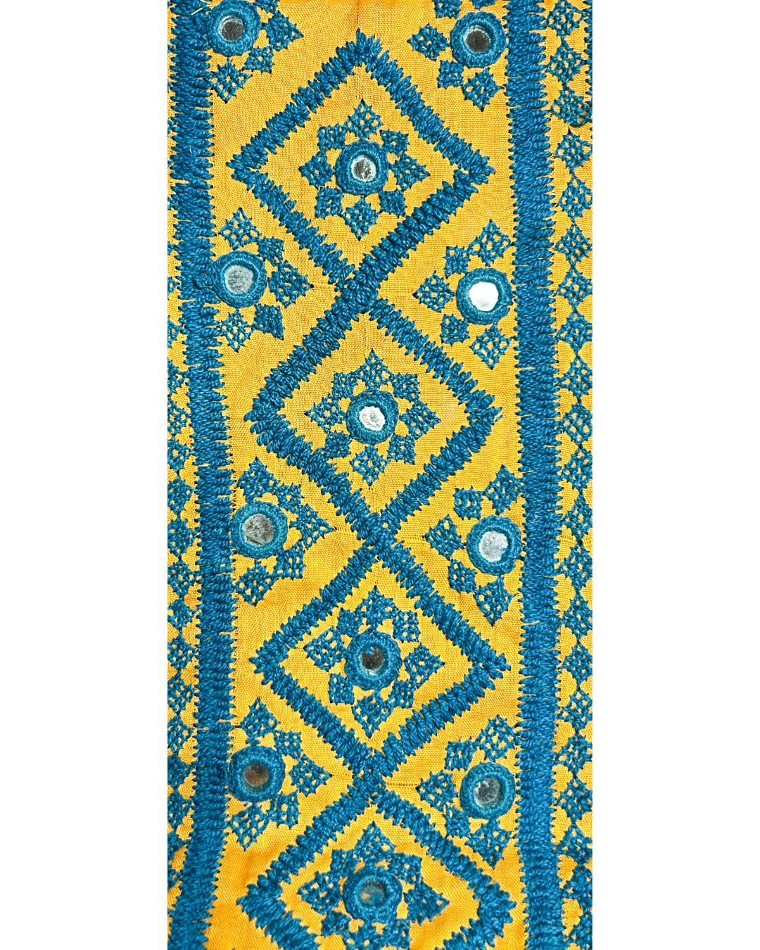 A handcrafted custom stamped cuff bracelet by Redd Dott Jewelry featuring turquoise embroidered diamond motifs with mirror accents on golden yellow fabric. A striking piece of embroidered jewelry and a bold rustic cuff bracelet.