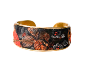 Orange and black floral embroidered cuff bracelet featuring intricate embroidery with delicate floral patterns in warm autumnal colors on a brass base.