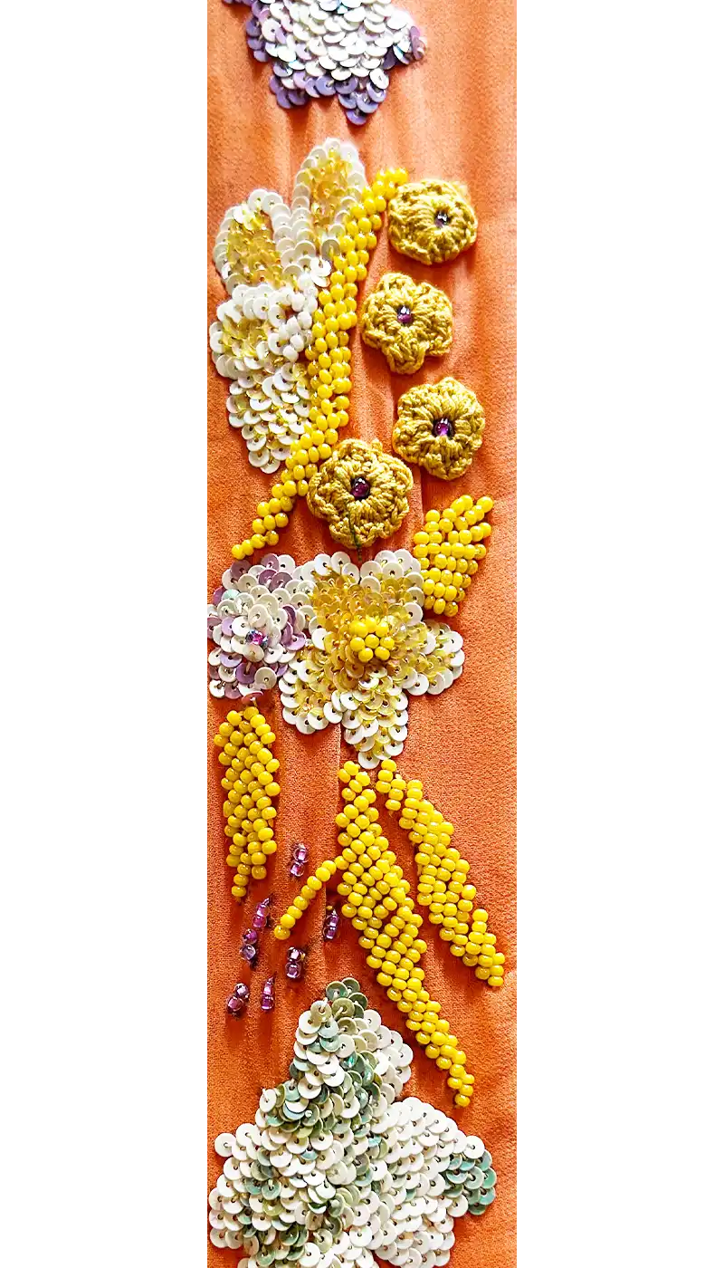 Close-up of Georgia floral cuff bracelet fabric – silky orange textile with yellow hand-sewn beads and white sequins forming delicate flowers, used in handmade brass cuff bracelets.