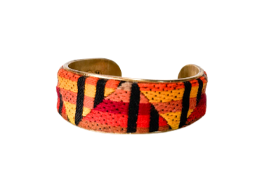 Red, yellow, and black Native Indian inspired fabric cuff bracelet featuring bold geometric patterns, reflecting traditional Native Indian artistry on a brass base.