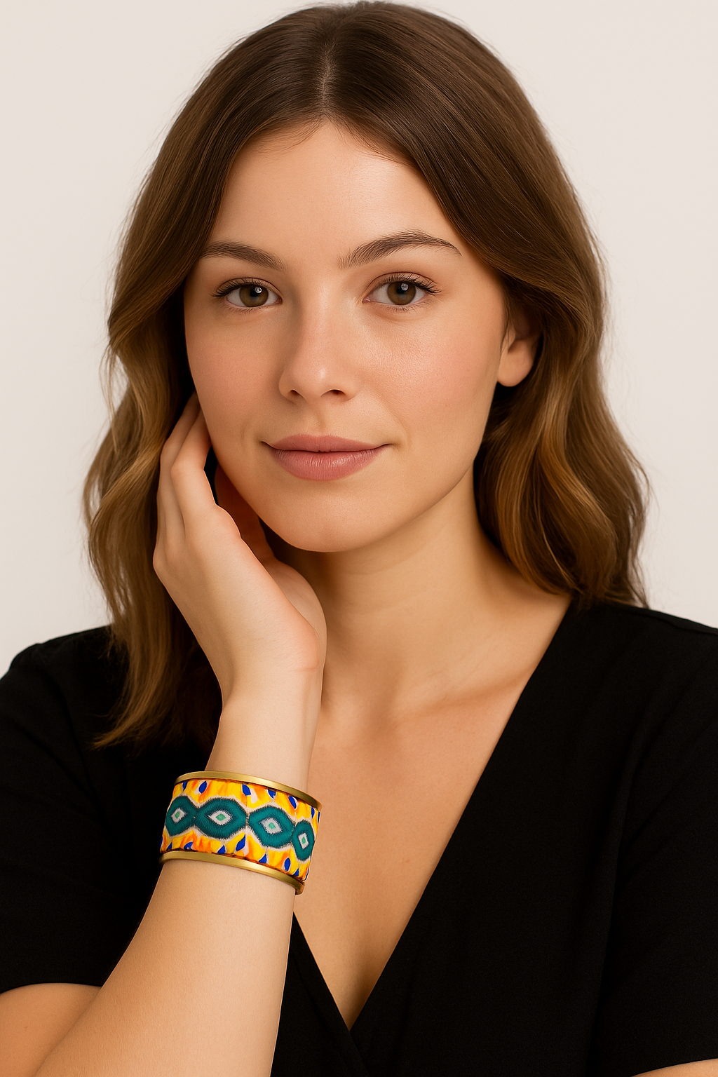 A woman wearing the Inga rustic brass cuff bracelet by Redd Dott Jewelry. The vibrant embroidered geometric pattern stands out against her black top, showcasing this inspirational jewelry piece handcrafted in Shreveport, LA.