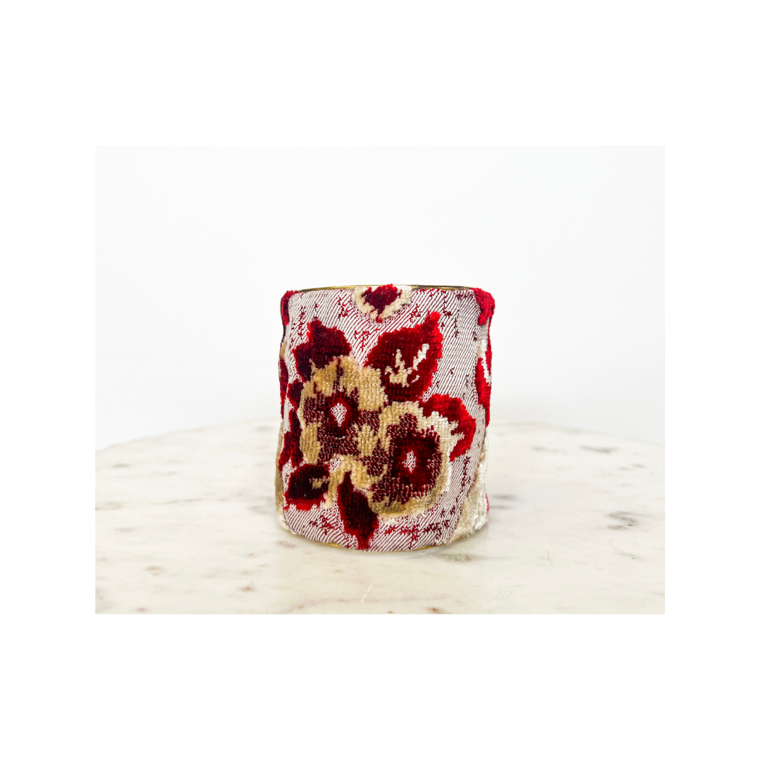 A small piece of ceramic with a red and yellow floral pattern on a white marble-like surface, reminiscent of an intricately designed floral cuff bracelet.