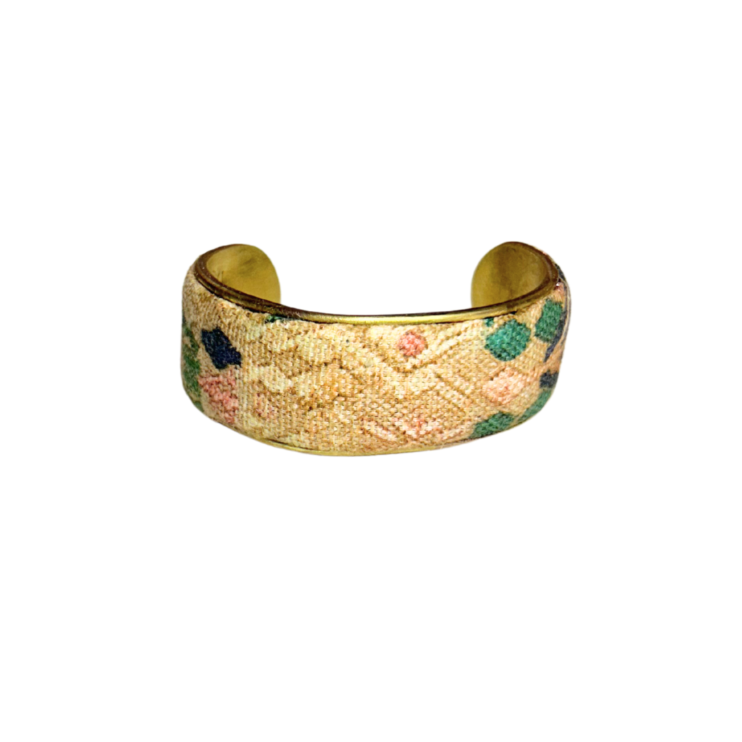 A handmade brass cuff bracelet from Redd Dott Jewelry, crafted and stamped in Shreveport, LA. Features a weathered tapestry-style fabric in ochre, green, and navy tones, giving it a rugged and timeless rustic cuff bracelet look.