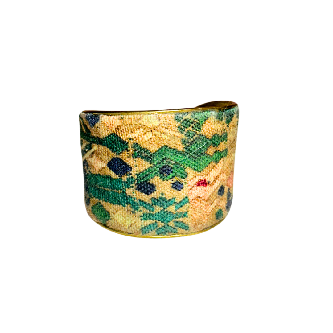 A handmade brass cuff bracelet from Redd Dott Jewelry, crafted and stamped in Shreveport, LA. Features a weathered tapestry-style fabric in ochre, green, and navy tones, giving it a rugged and timeless rustic cuff bracelet look.