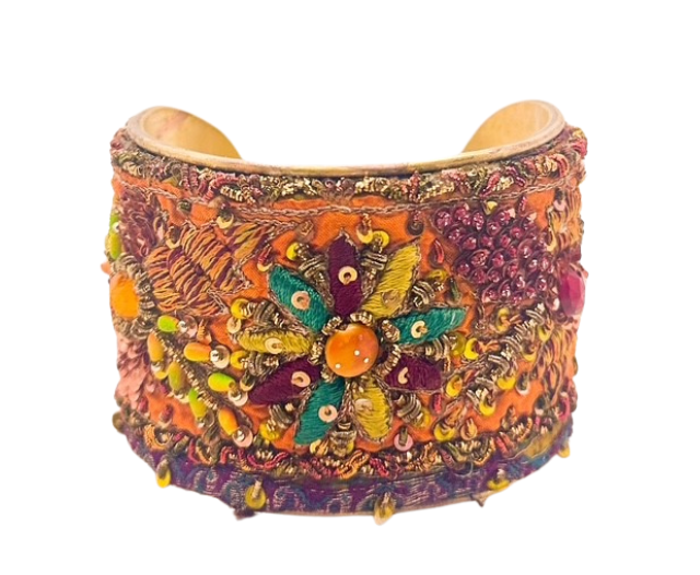 The Josephine cuff bracelet by Redd Dott Jewelry features bold orange fabric with embroidered floral patterns and beadwork on a vintage brass base. Handcrafted with a hand-stamped message inside.