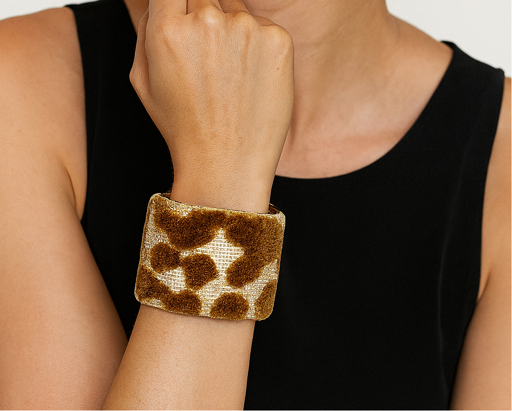 A female model’s wrist adorned with a 2-inch raw brass cuff bracelet featuring soft brown flocked circles on an ivory background—an elegant one of a kind jewelry statement in cuff bracelets for women.