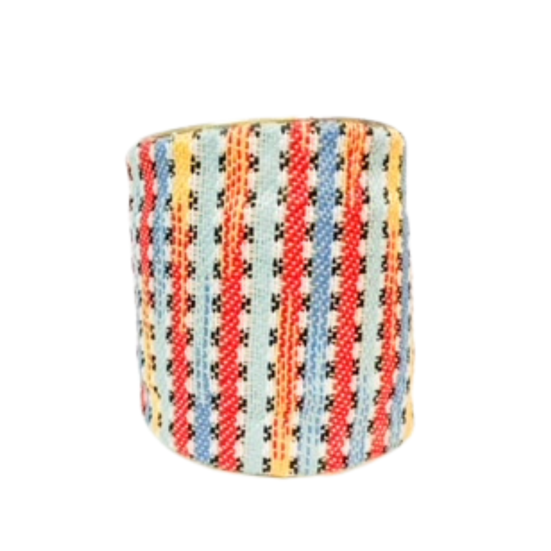 A 3-inch one of a kind jewelry brass cuff bracelet for women wrapped in multicolor woven fabric featuring diagonal coral, blue, yellow, and mint stripes with black cross-stitch accents, shown against a white background.