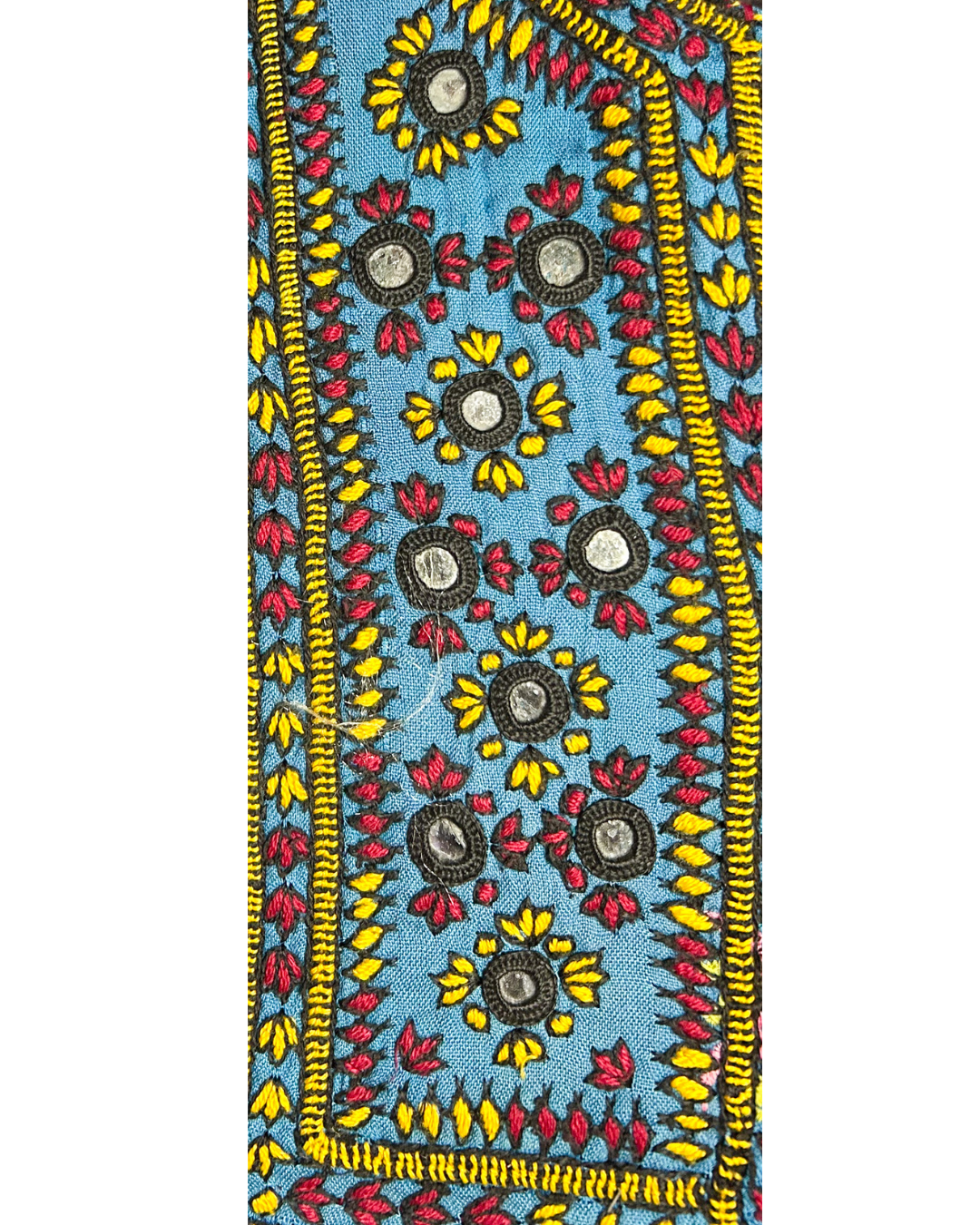 A handcrafted custom stamped cuff bracelet by Redd Dott Jewelry featuring red, yellow, and black floral embroidery with mirrors on blue fabric. A bold, folk-inspired vintage brass bracelet and intricate piece of embroidered jewelry.