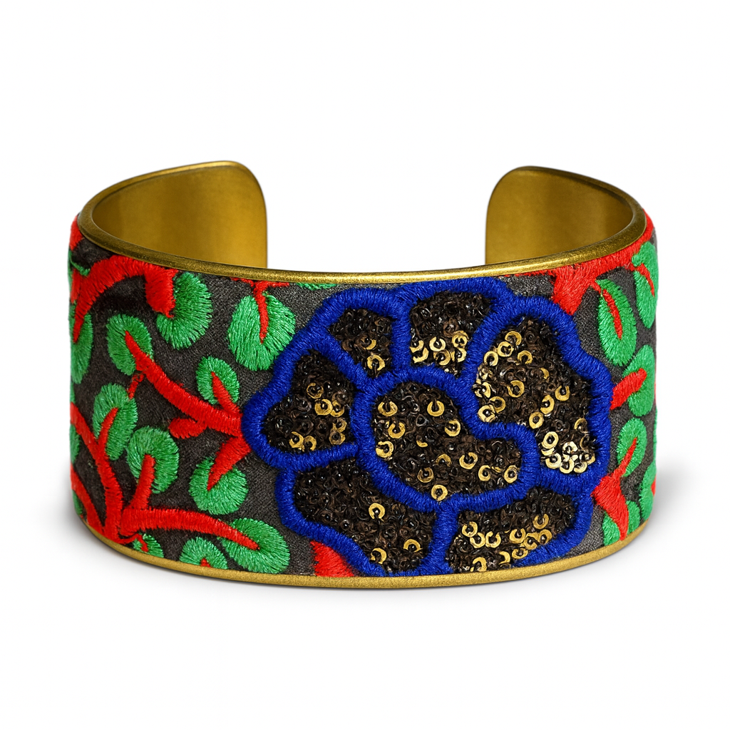 Model wearing the Redd Dott Cypress 2-inch cuff bracelet, featuring bold blue and black floral embroidery with red and green accents, framed in gold for a striking statement look.