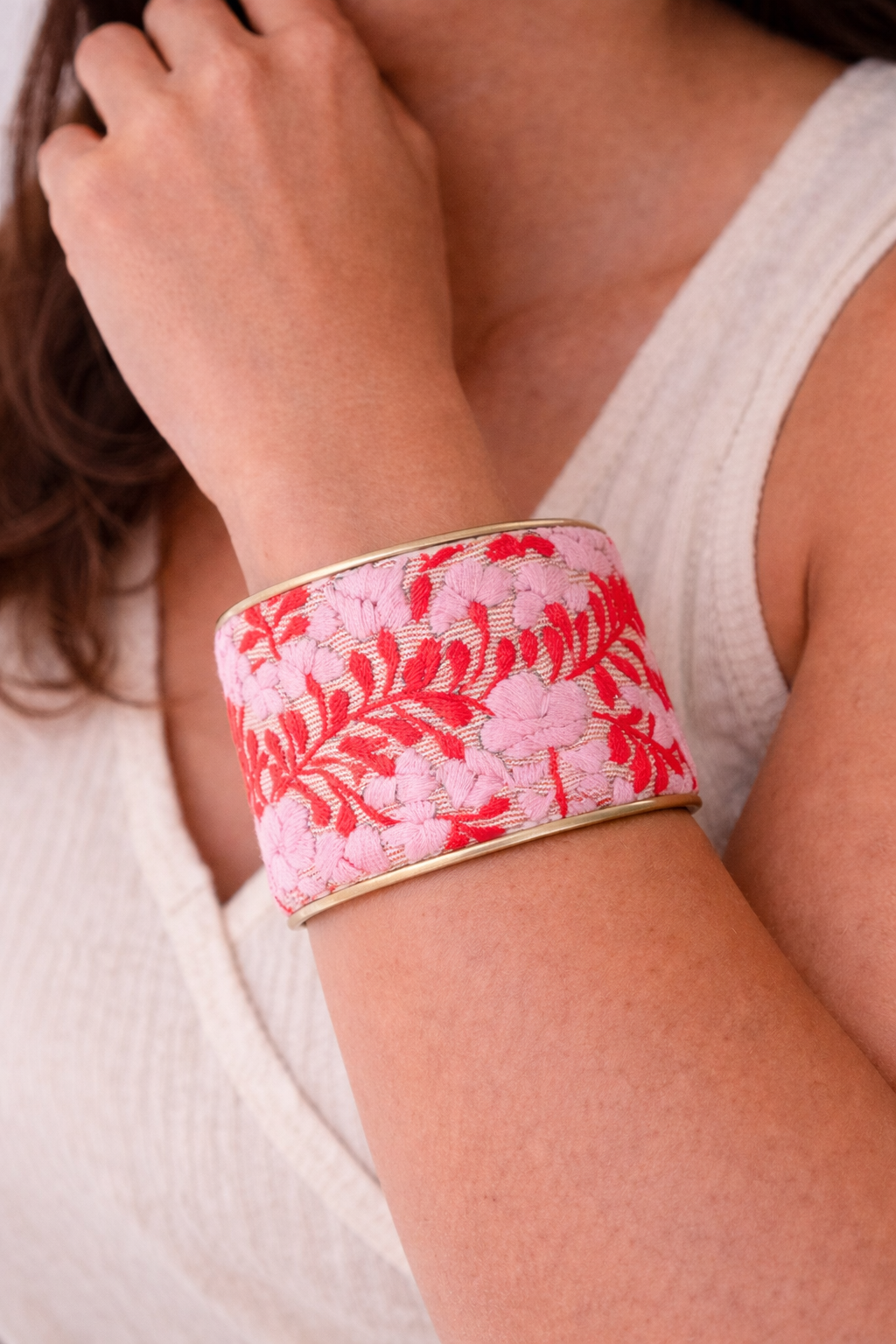 2-inch Corazón Rojo cuff bracelet worn on models wrist showcasing red floral embroidery on a subtle red striped background