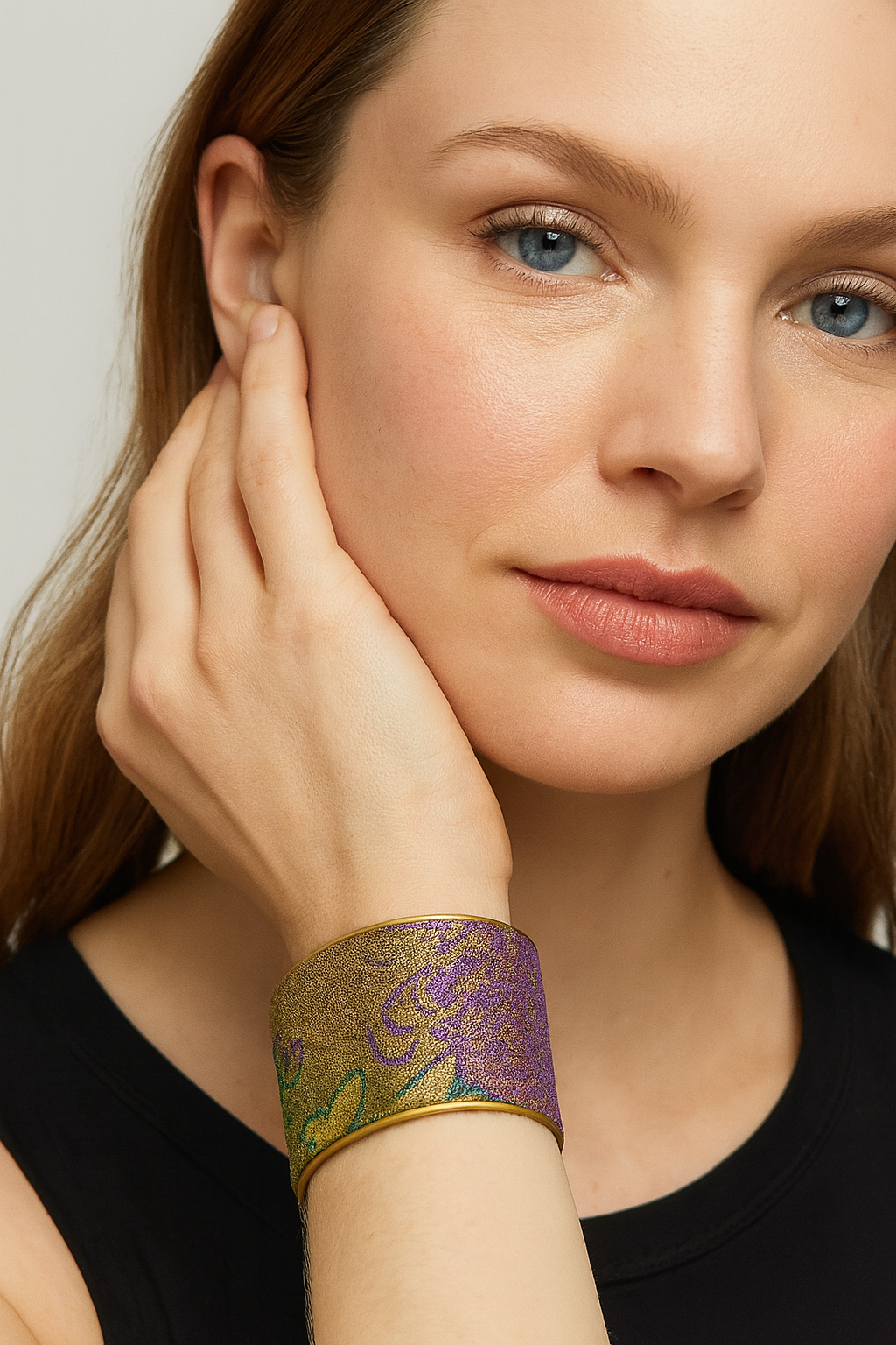 Close-up of the Redd Dott Parade On 2-inch cuff bracelet, showcasing shimmering metallic fabric in purple, gold, and green with an abstract floral pattern, framed in a sleek gold trim for a bold and artistic finish.