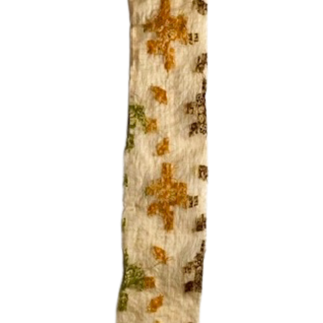 Vintage brass bracelet with a cream fabric overlay featuring golden, green, and brown embroidered cross patterns, custom-stamped and handmade by Redd Dott Jewelry.