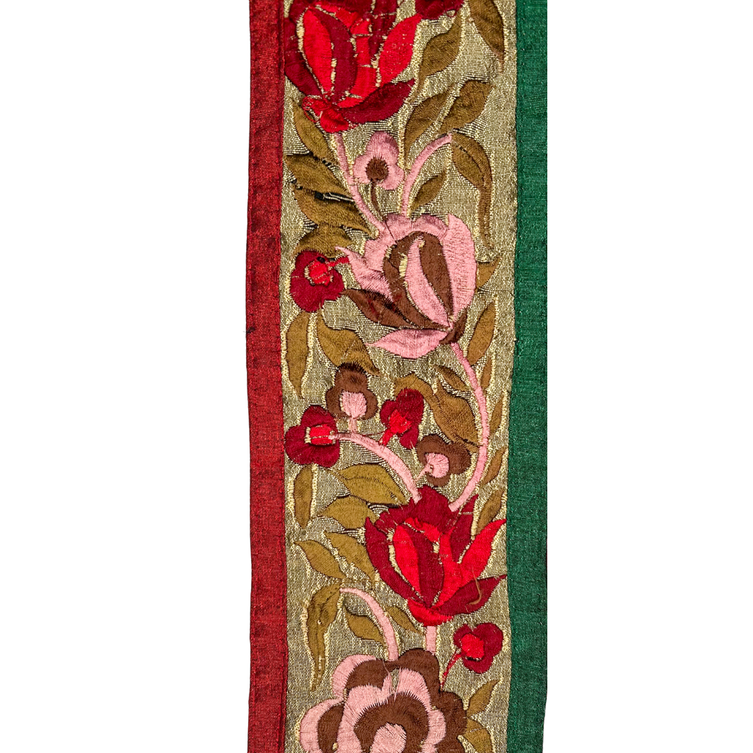 A luxury flower bracelet by Redd Dott Jewelry, featuring rich red and blush floral embroidery on a shimmering gold background. Framed with deep red and green borders.