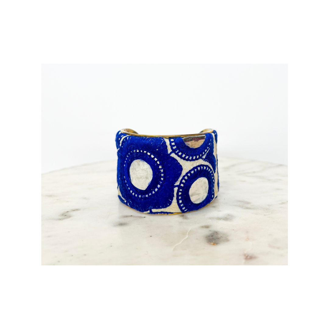 A Spring Floral Cuff Bracelet with a blue and white circular pattern displayed on a light marble surface.