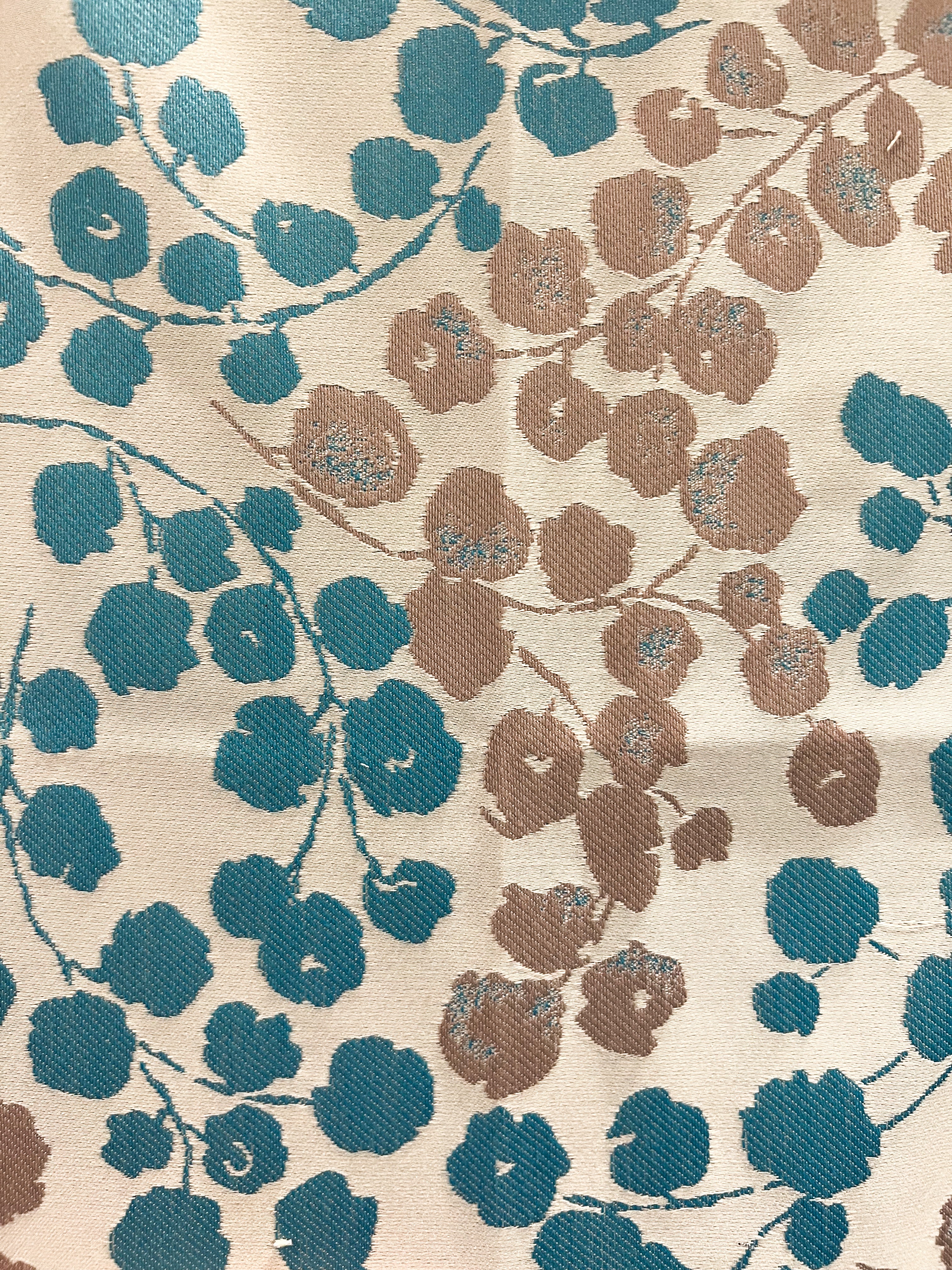 Close-up of Blossom cuff fabric – cream jacquard fabric with teal and taupe cherry blossom floral embroidery, designed for a custom stamped brass cuff bracelet.