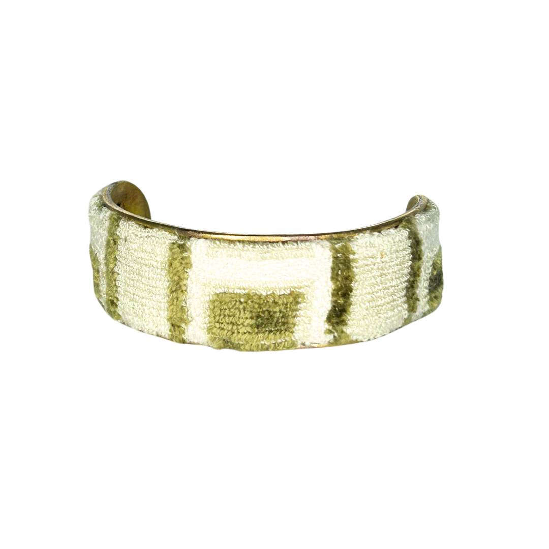 A brass cuff bracelet by Redd Dott Jewelry wrapped in a soft, textured fur bracelet fabric featuring a moss green and cream block pattern with a raised, velvety finish.