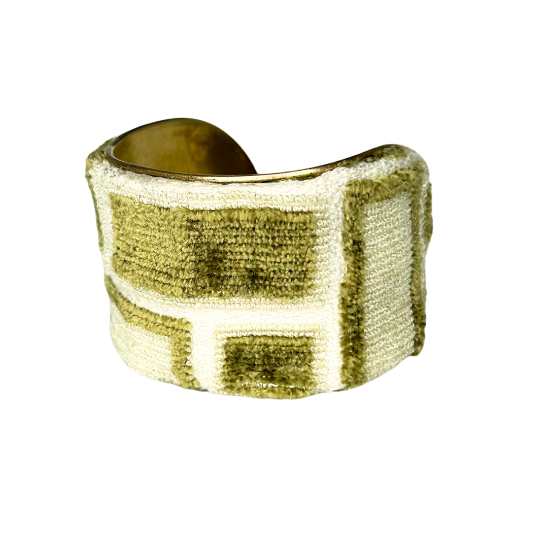 A brass cuff bracelet by Redd Dott Jewelry wrapped in a soft, textured fur bracelet fabric featuring a moss green and cream block pattern with a raised, velvety finish.