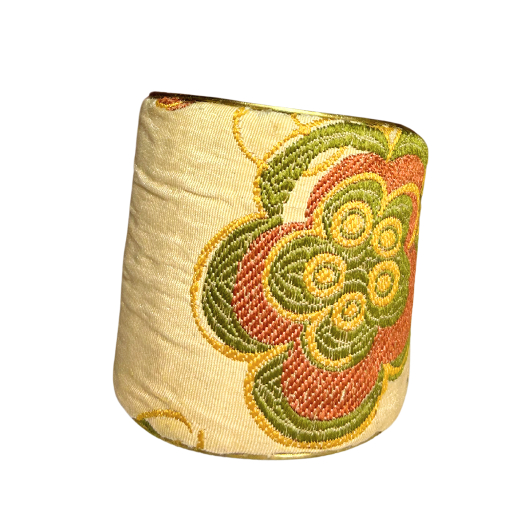 The Anna-claire brass cuff bracelet features an embroidered floral design in warm tones of green, gold, and coral on a soft champagne base. This vintage gold cuff bracelet is a graceful power bracelet that radiates timeless elegance and strength.