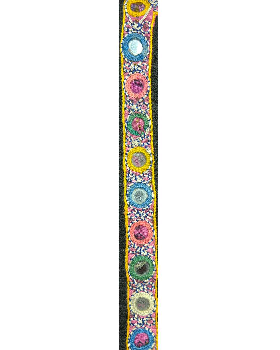 A handcrafted custom stamped cuff bracelet by Redd Dott Jewelry made from colorful kaftan fabric with circular mirrored embroidery and bright stitched details. A striking piece of embroidered jewelry.