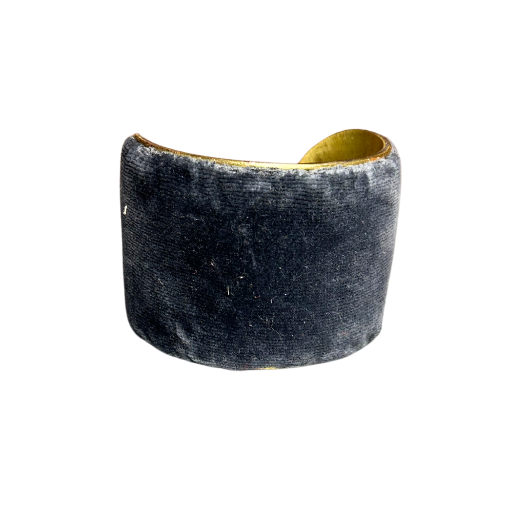 A handmade brass cuff bracelet, crafted and stamped in Shreveport, LA. Features a wide silhouette wrapped in deep blue-gray velvet with a soft texture, creating a muted and elegant rustic cuff bracelet look.