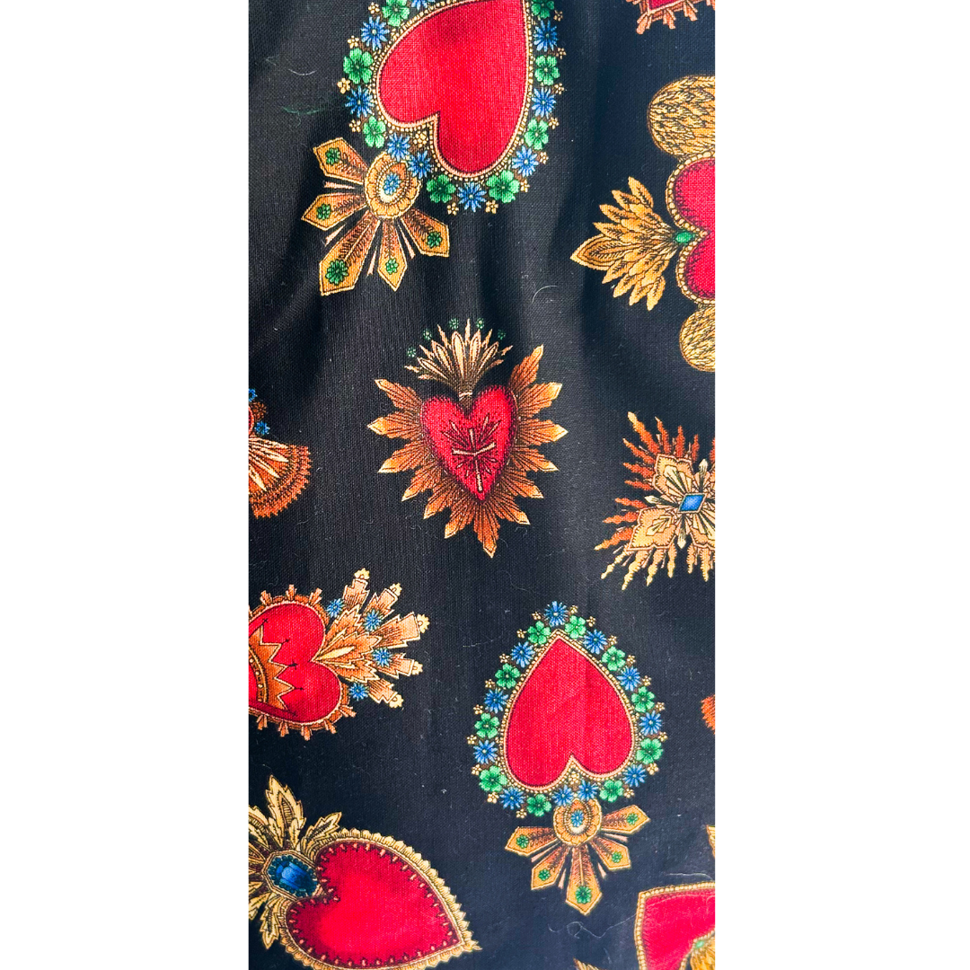 A custom stamped cuff bracelet by Redd Dott Jewelry, featuring a dramatic sacred heart motif with golden rays, jewel-toned accents, and red heart imagery on a black background. This gold cuff bracelet is a bold and elegant piece, combining vintage charm with artistic detailing.