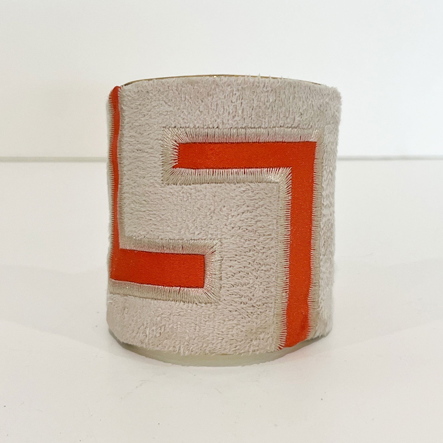 A 3-inch brass cuff bracelet featuring ivory velvet with vibrant orange embroidered angles, showcasing the bold structure of a rustic cuff bracelet and the intention of inspirational jewelry by Redd Dott Jewelry.