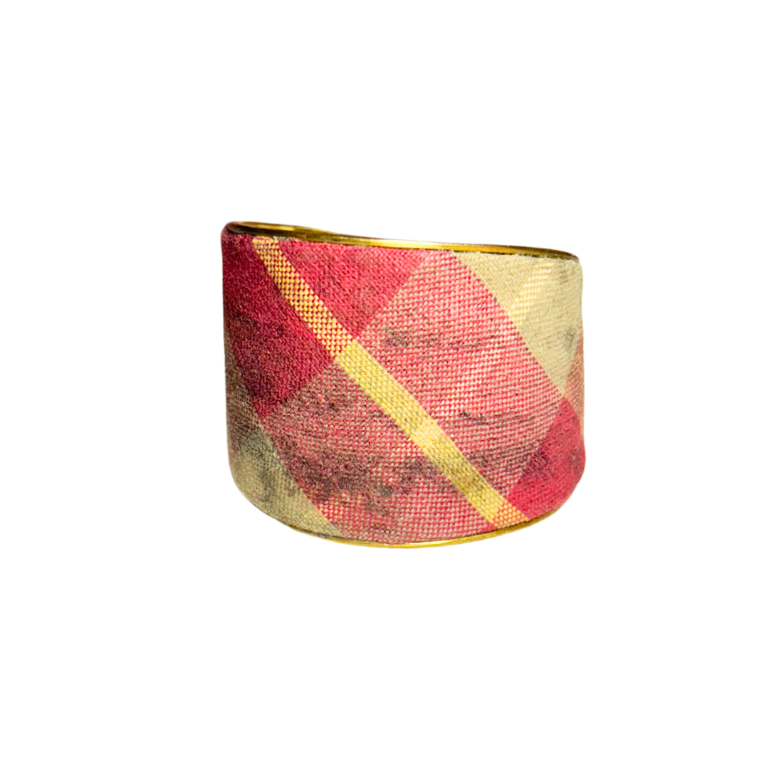 A handcrafted brass cuff bracelet by Redd Dott Jewelry wrapped in red and ivory plaid fabric with a vintage, worn-in finish. A cozy, elegant vintage brass bracelet with timeless appeal.