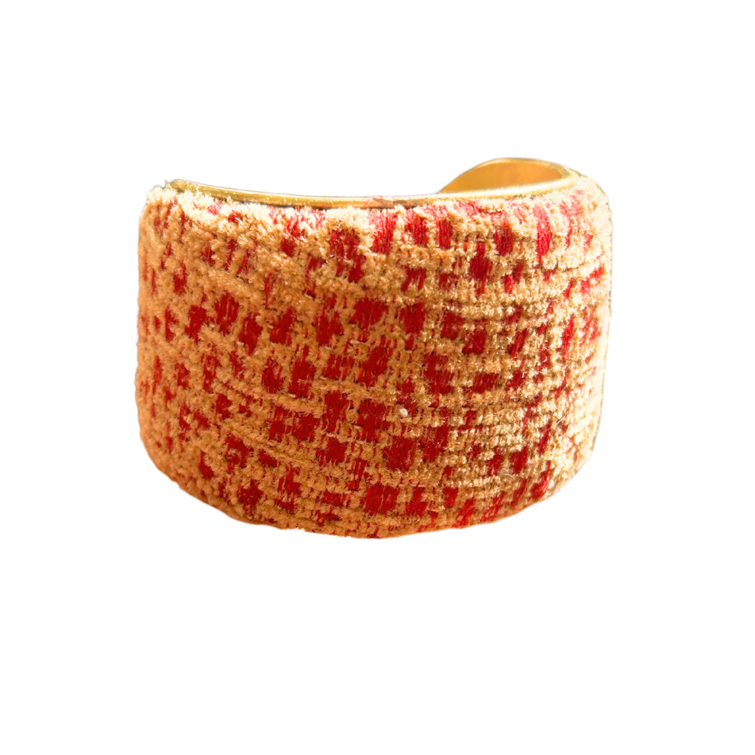 Laszlo cuff bracelet – 2-inch wide brass cuff wrapped in rust red and beige woven fabric with a textured, grid-like pattern and a warm, golden interior.