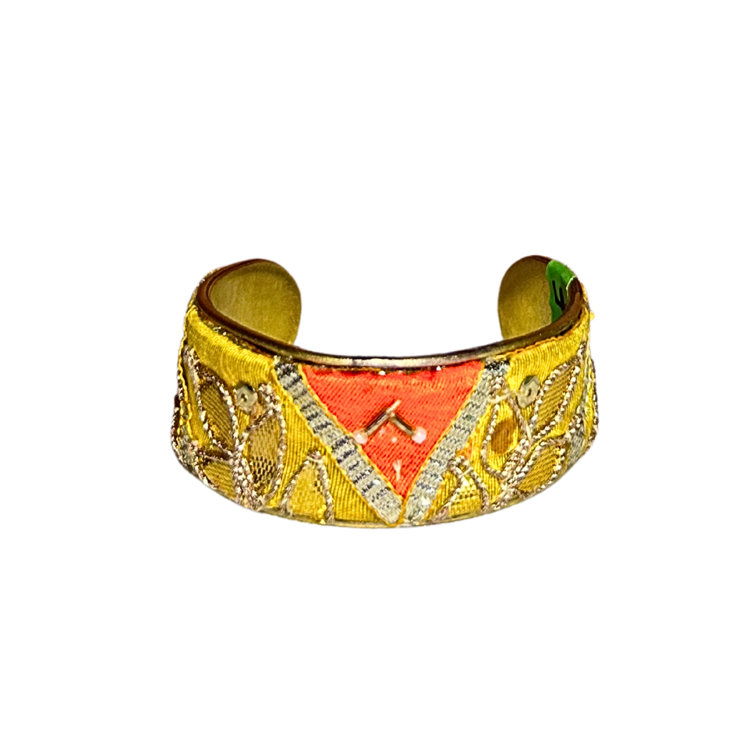 A handcrafted brass cuff bracelet by Redd Dott Jewelry featuring a warm yellow background with metallic embroidery and chevron symbolism. A radiant and elegant piece of inspirational jewelry.