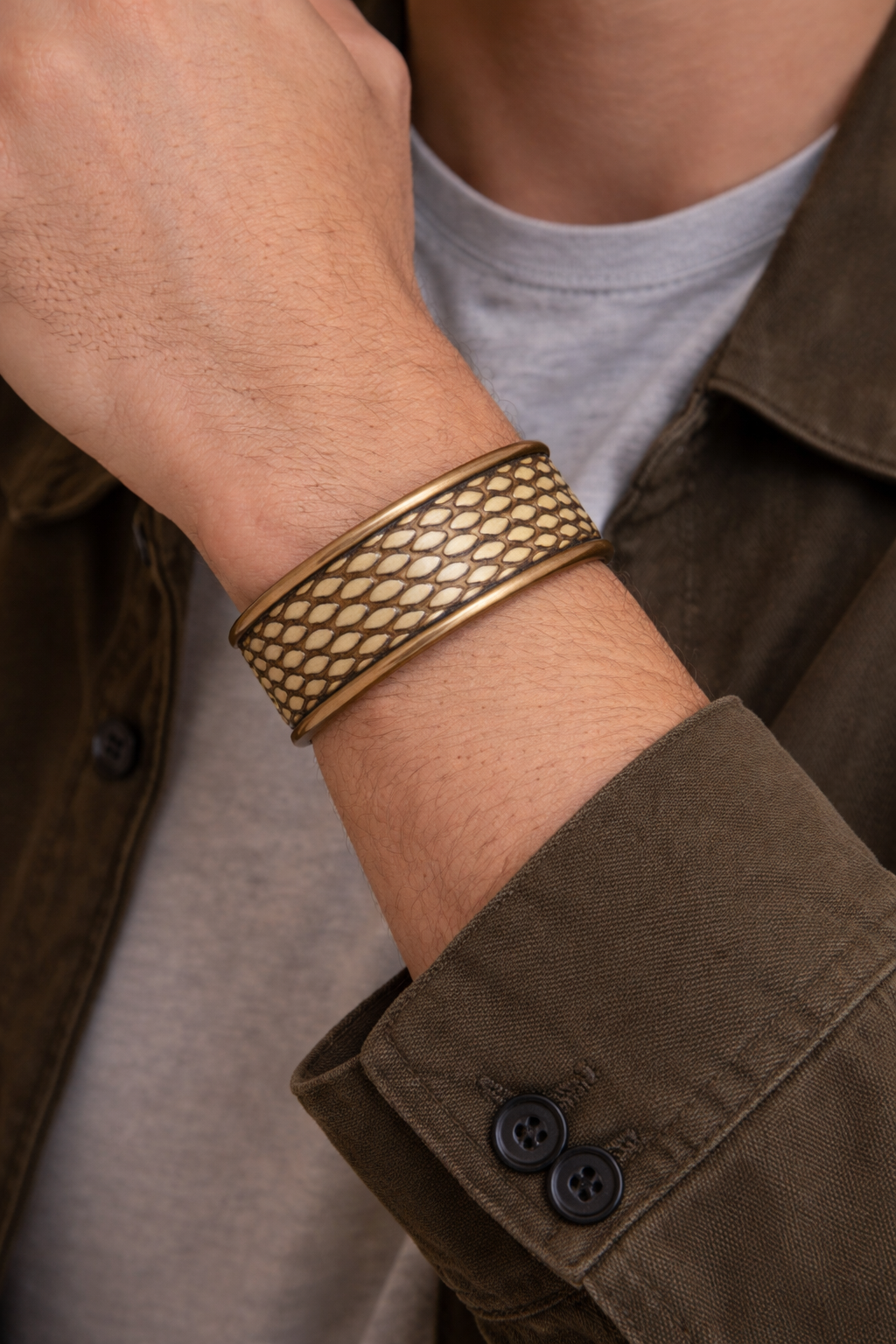 Close-up of a model wearing the men’s 1-inch eastern brown snake cuff bracelet by Redd Dott Jewelry, showcasing a warm tan and honey-toned snake skin pattern with fine oval scales, framed by smooth brass edges that emphasize the natural texture and handcrafted cuff bracelet detail, handcrafted in Shreveport, LA by Redd Dott Jewelry.