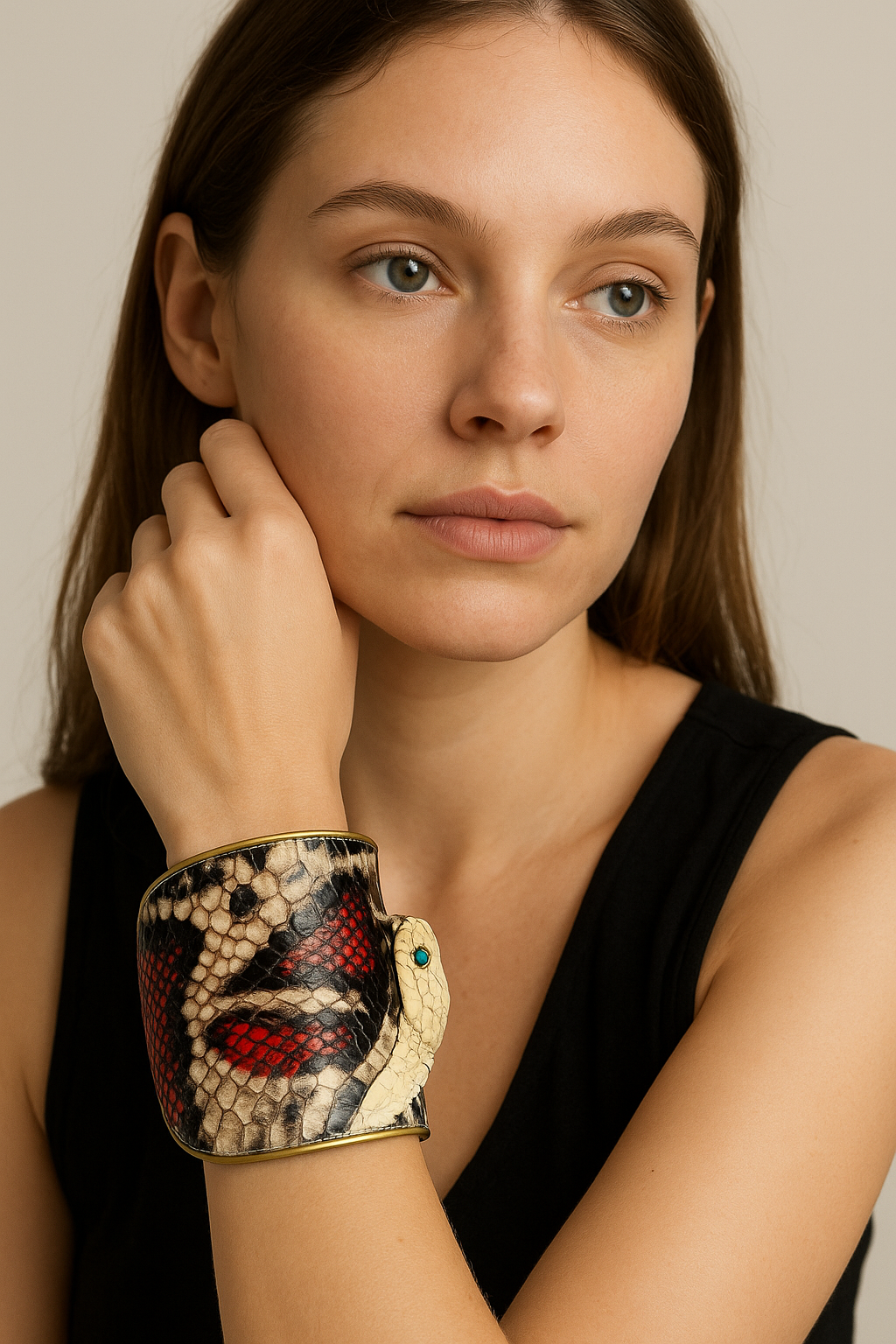 Female model wearing a gold brass cuff made from genuine red king cobra skin, with preserved cobra head and turquoise eyes, styled with a sleeveless black top.