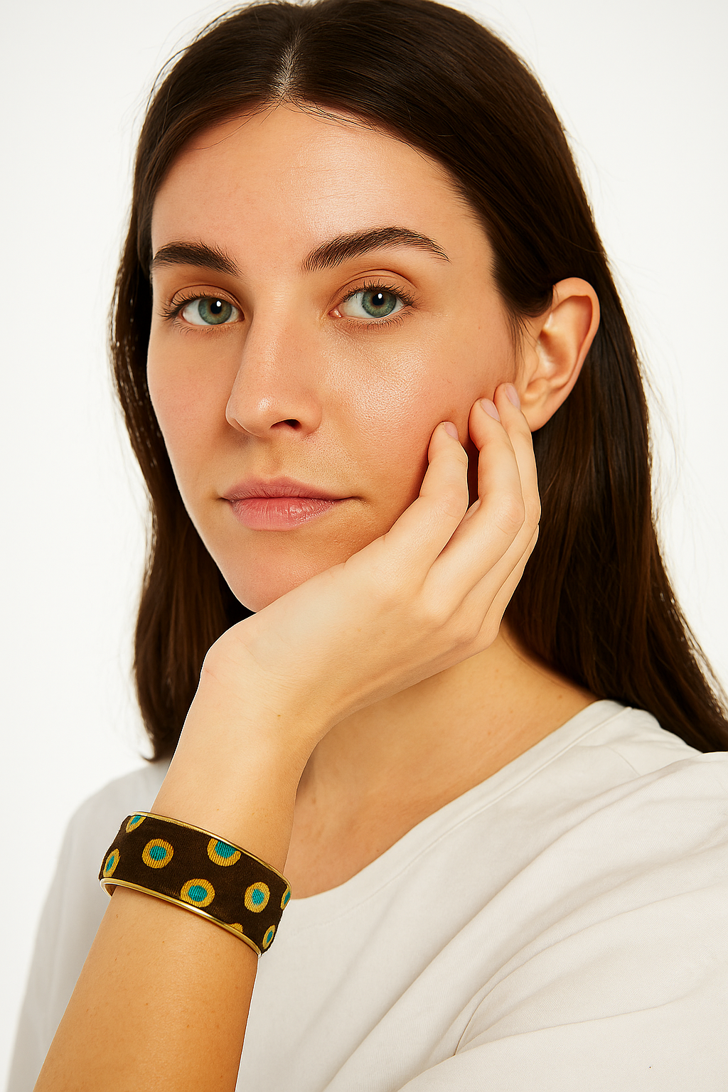 A female model wearing a one of a kind jewelry brass cuff bracelet for women—a 1-inch wide, open-back design wrapped in brown fabric with aqua-and-yellow dot motifs, shown on her wrist against a neutral backdrop.