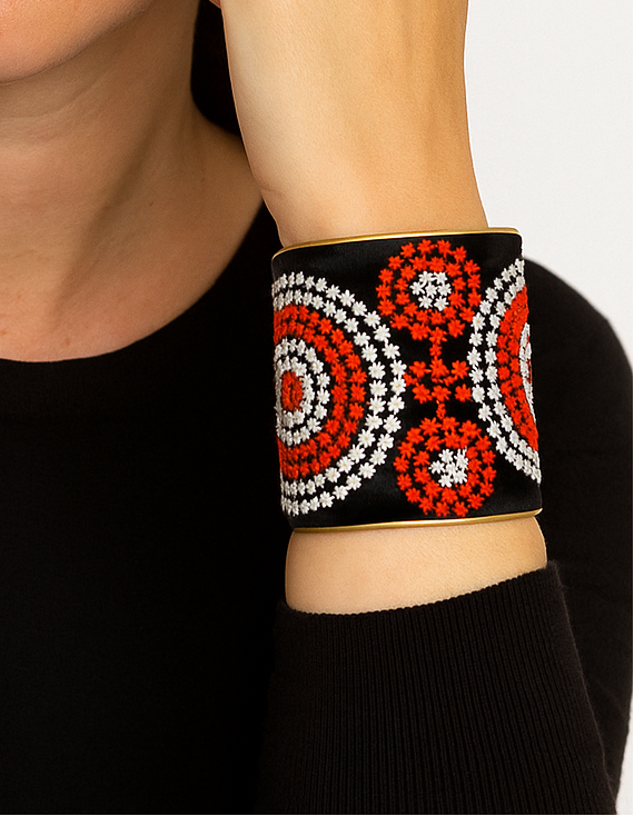 Wide embroidered cuff bracelet with red, white, and black geometric circles worn on model’s wrist, bold statement jewelry in brass base, handcrafted in Shreveport, LA by Redd Dott Jewelry.