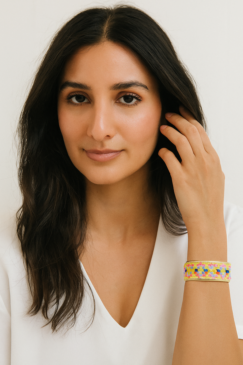 A woman wearing a 1-inch brass cuff bracelet with a vivid neon geometric woven pattern in pink, yellow, blue, and orange—styled as a fun and uplifting piece of inspirational jewelry and bold geometric bracelet.