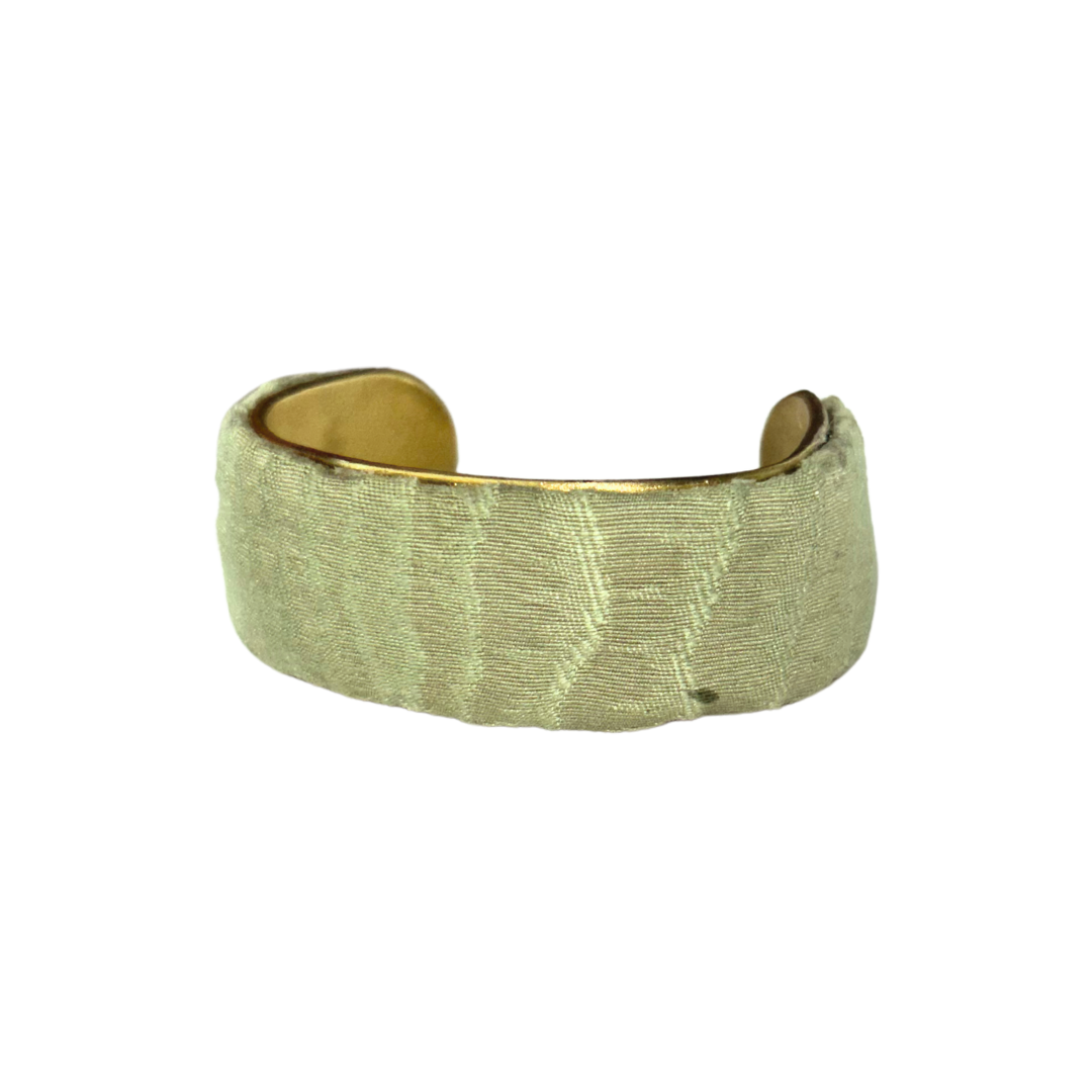 Owlen 1-inch cuff bracelet – pale green embroidered fabric with soft woodgrain or wave-like stitching, wrapped around a slim brass base.