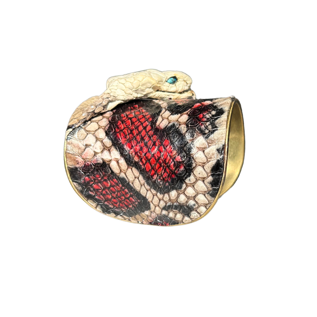 right side view of A handcrafted nature inspired jewelry cuff bracelet by Redd Dott Jewelry featuring real king cobra skin in black, ivory, and red, with a cobra head detailed with genuine turquoise eyes. Fierce, sculptural, and richly textured.