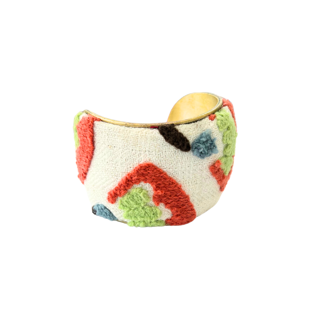 Silviya 2-inch cuff bracelet – cream boucle-textured fabric with tufted geometric shapes in coral, green, blue, and brown, set on a handcrafted golden brass base.